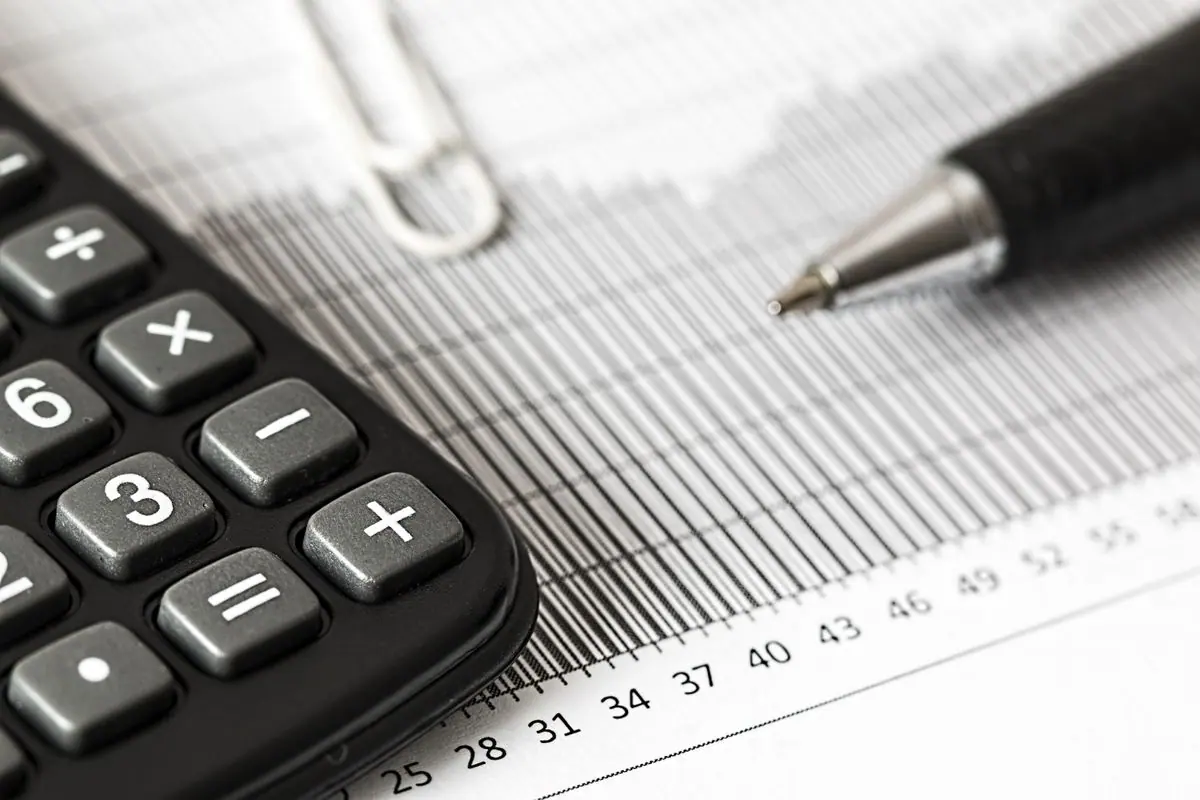 Escritorio con billetes, calculadora y una laptop para gestión financiera